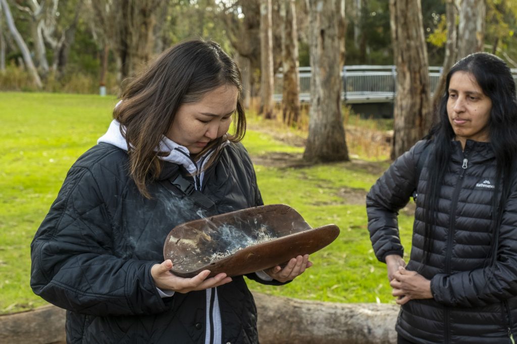 Tuvshe (left) participates in a traditional smoking ceremony at the Living Kaurna Cultural Centre in Adelaide during a study tour organised by Australia Awards to celebrate NAIDOC week. 