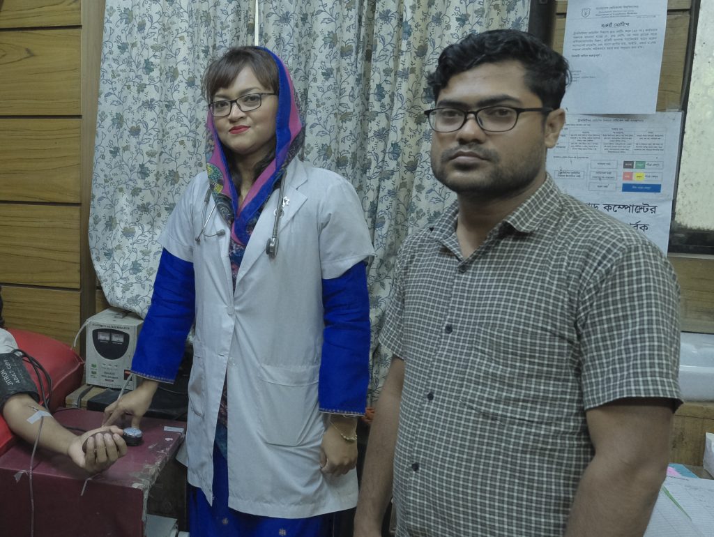 Farah (left) seen taking a blood sample of a patient with her colleague (right).