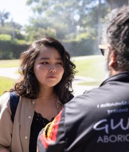 A young alumna speaking with an Aboriginal cultural guide outdoors