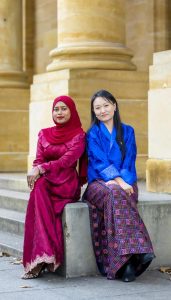 Two alumnae seated together outside a university building