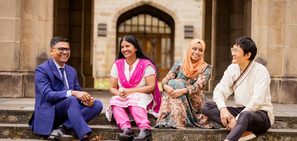 Four Australia Awards alumni seated together on university steps