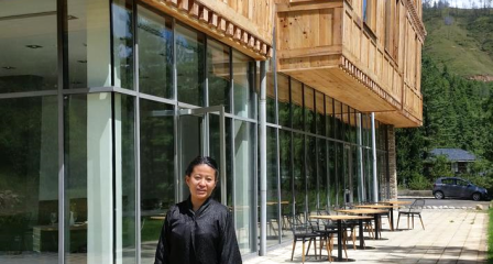 Sonam Peldon standing outside a timber building